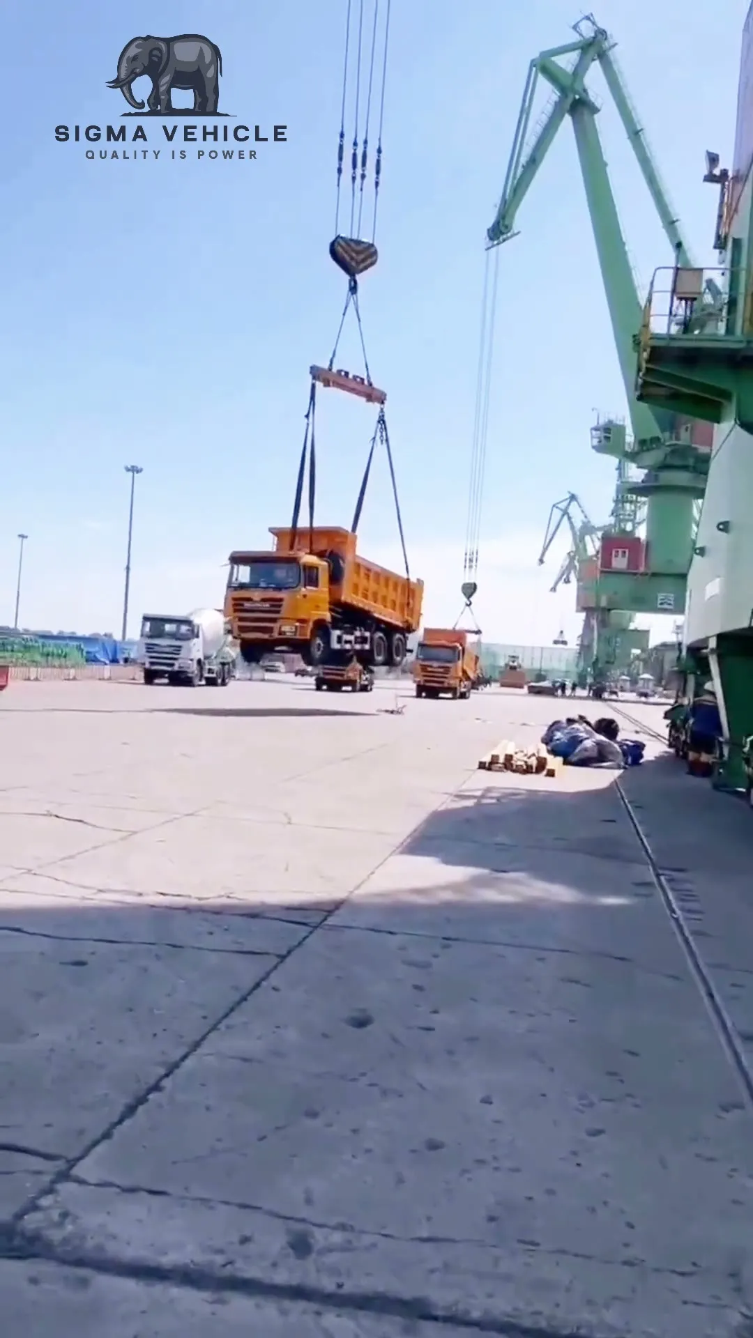 Orange 6x4 dump truck lifted by a port crane during loading for export